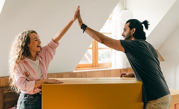 man and woman performing a high five while moving into a house